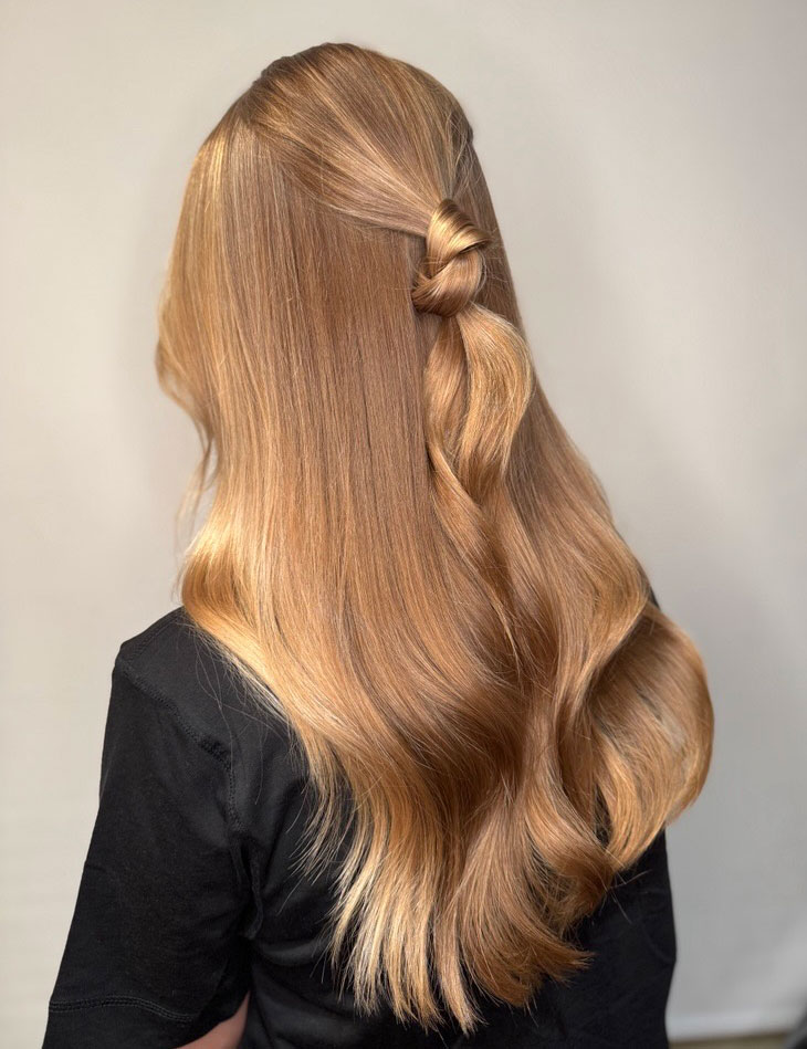 Hår i cashmere bronde med lyse highlights rundt ansiktet, stylet med løse bølger.
