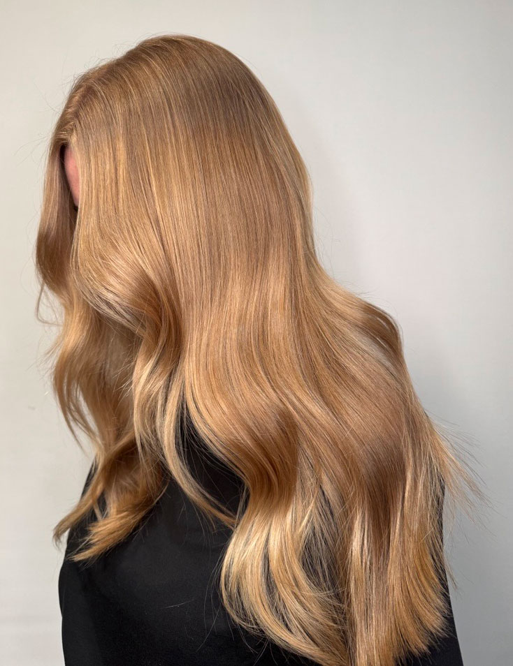 Kvinne med naturlig bølget hår i cashmere bronde, glansfull finish og varme undertoner.