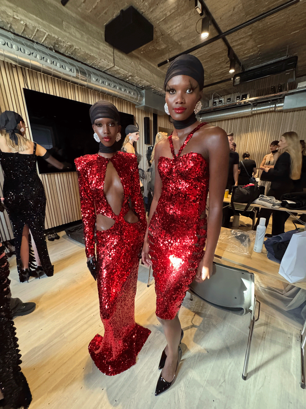 To modeller i røde paljettkjoler med hår og styling av Nikita Hair backstage på Oslo Runway.