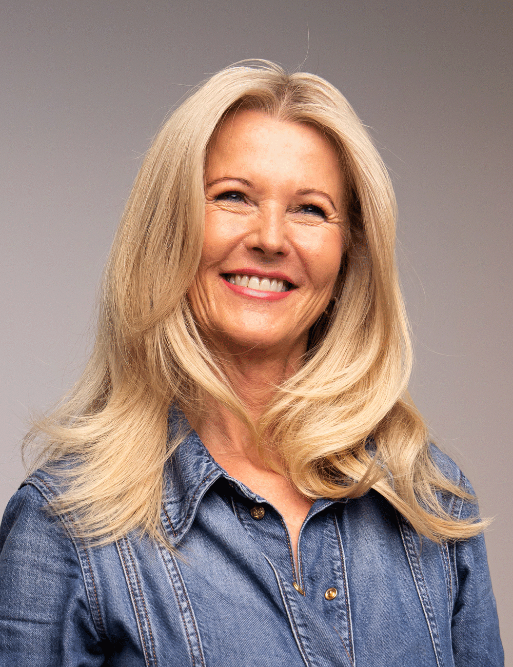 Kvinne med glansfull blowout og naturlig volum i håret – Nikita Hair