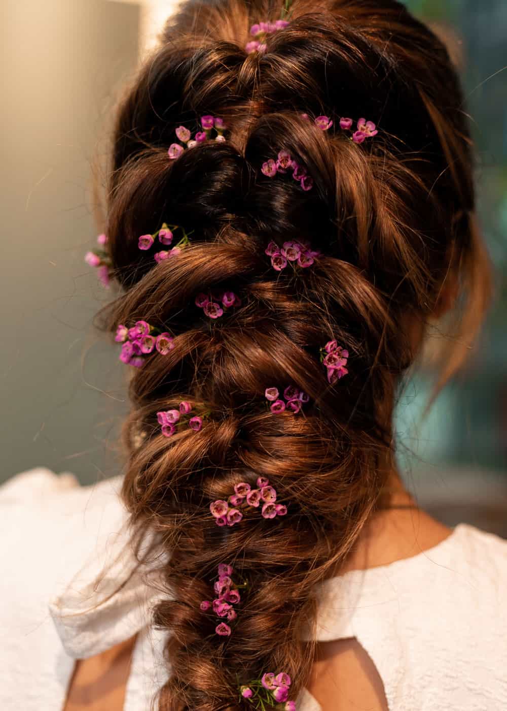 fyldig flette med små blomster som romantisk festfrisyre